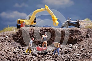 MiniatureÃÂ Contruction workers working lifting stone using shovel